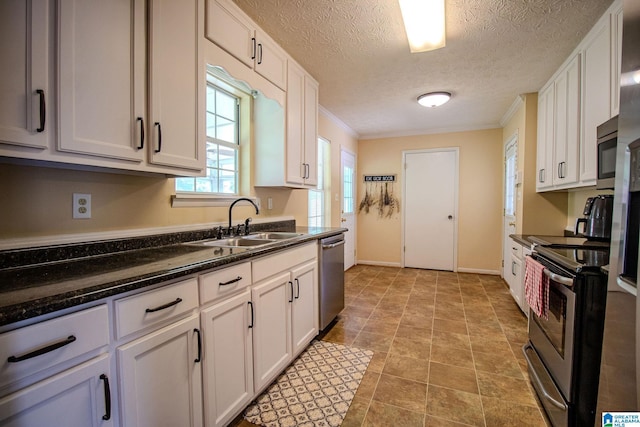 kitchen with a sink, stainless steel appliances, white cabinets, crown molding, and baseboards