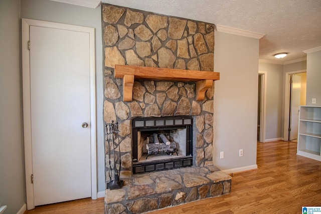 details with a textured ceiling, baseboards, crown molding, wood finished floors, and a fireplace