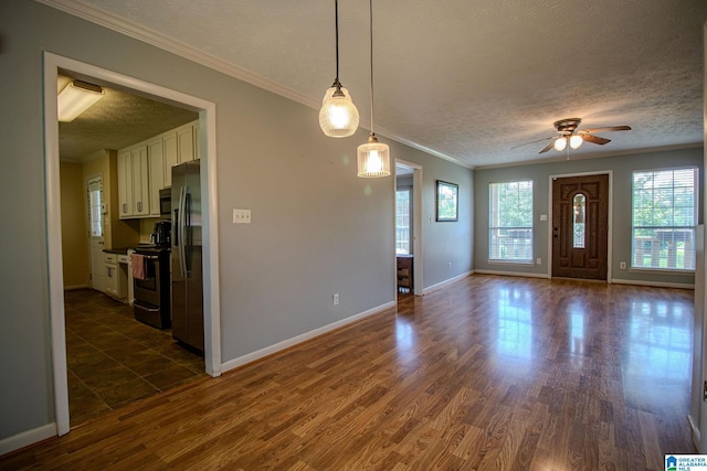 foyer featuring ceiling fan, a textured ceiling, baseboards, and a healthy amount of sunlight