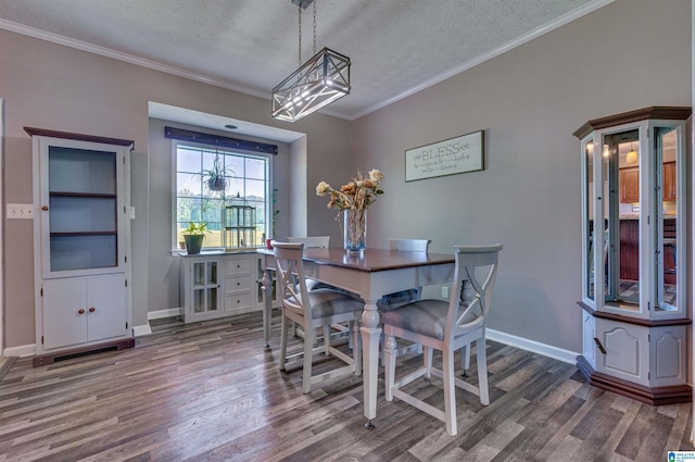dining area featuring wood finished floors, a textured ceiling, an inviting chandelier, crown molding, and baseboards