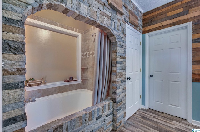bathroom with tiled shower / bath combo and wood finished floors