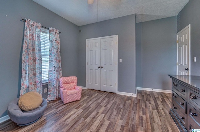 sitting room featuring a textured ceiling, dark wood-style flooring, and baseboards