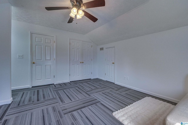 unfurnished bedroom with baseboards, lofted ceiling, a closet, and ceiling fan