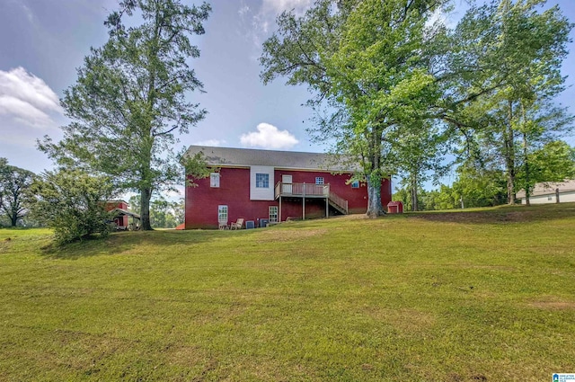 rear view of house with stairs, a wooden deck, and a lawn