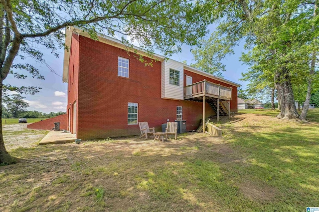 rear view of property featuring a yard, brick siding, central AC unit, stairway, and a wooden deck