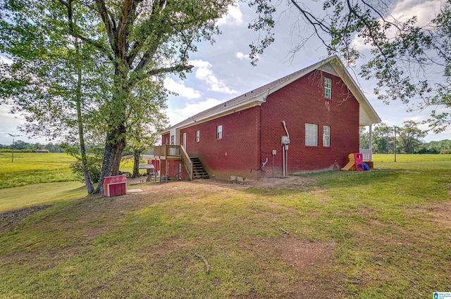 view of home's exterior with a yard, brick siding, and stairway