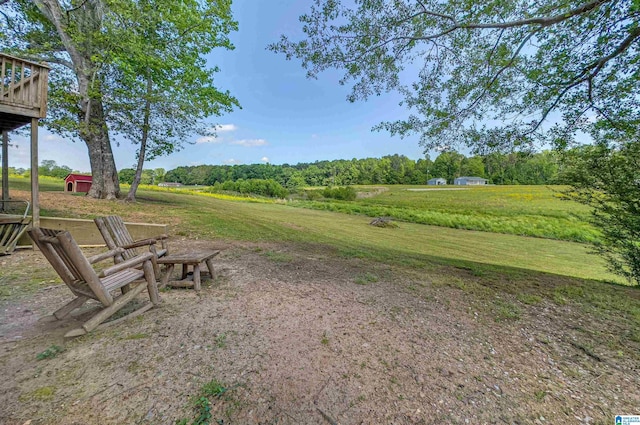 view of yard featuring an outdoor structure, a rural view, and a shed