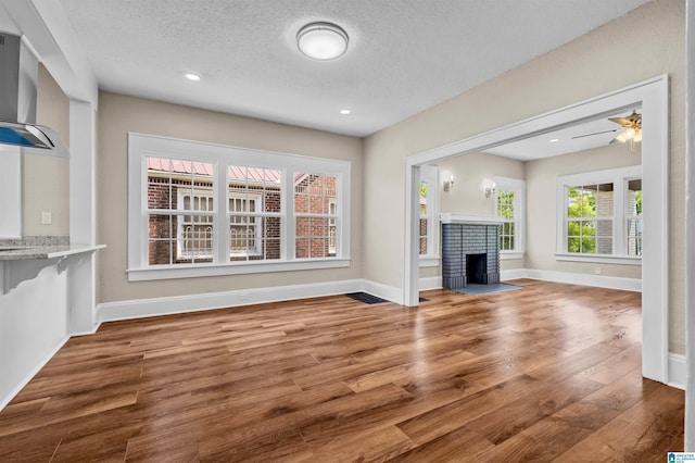 1330 Bush Blvd W, Birmingham, AL 35208 - unfurnished living room with wood finished floors, baseboards, a fireplace, a textured ceiling, and recessed lighting
