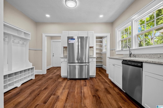 1330 Bush Blvd W, Birmingham, AL 35208 - kitchen featuring appliances with stainless steel finishes, a sink, dark wood-style flooring, light stone countertops, and white cabinetry