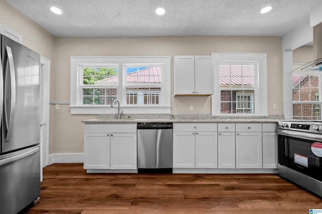 1330 Bush Blvd W, Birmingham, AL 35208 - kitchen with appliances with stainless steel finishes, a sink, white cabinets, light stone countertops, and a textured ceiling