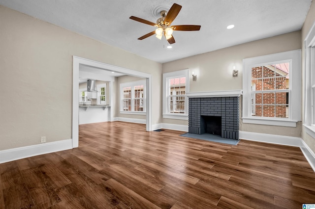1330 Bush Blvd W, Birmingham, AL 35208 - unfurnished living room featuring a ceiling fan, a brick fireplace, baseboards, wood finished floors, and recessed lighting