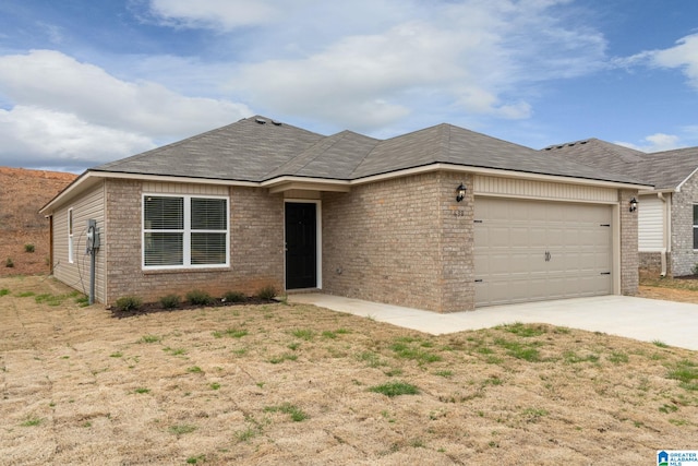 single story home featuring driveway, a shingled roof, brick siding, and a garage