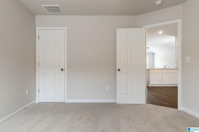 unfurnished bedroom with carpet, visible vents, baseboards, and a sink