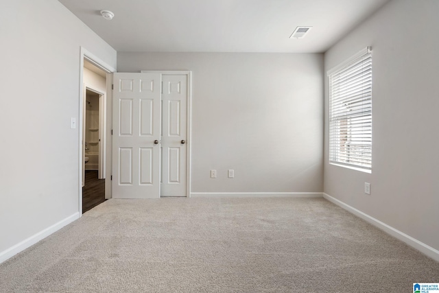 unfurnished bedroom with carpet, visible vents, multiple windows, and baseboards