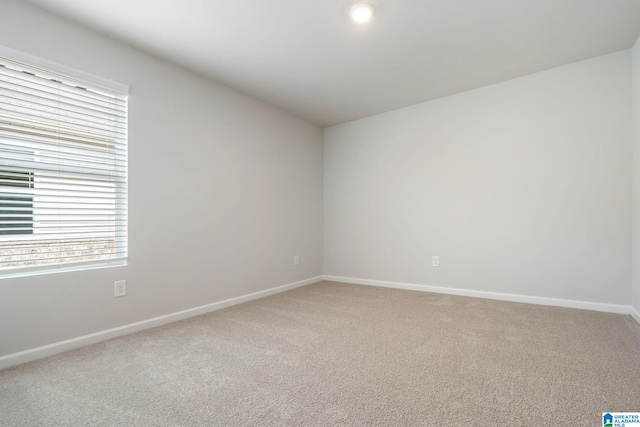 unfurnished room with baseboards, light carpet, and vaulted ceiling