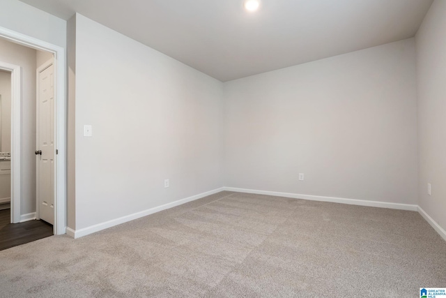 empty room featuring baseboards and dark carpet