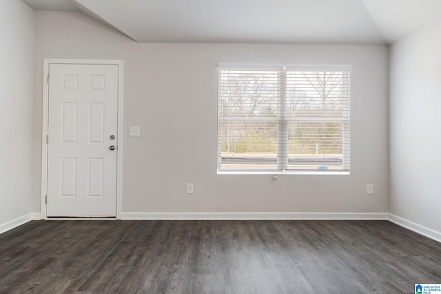 empty room with vaulted ceiling, dark wood-type flooring, and baseboards