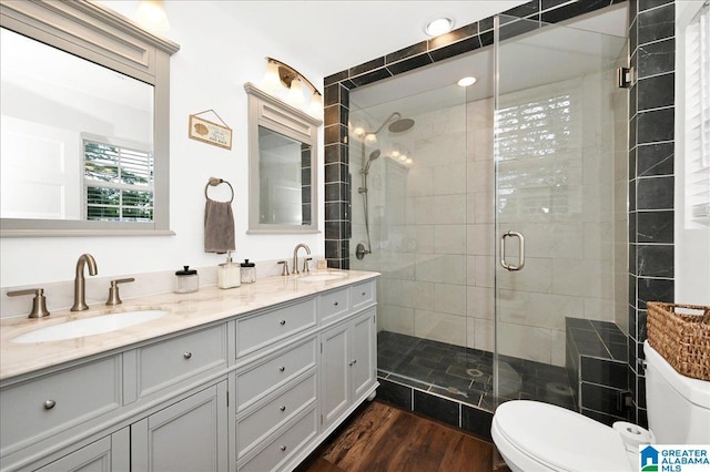 bathroom featuring toilet, wood finished floors, a stall shower, and a sink