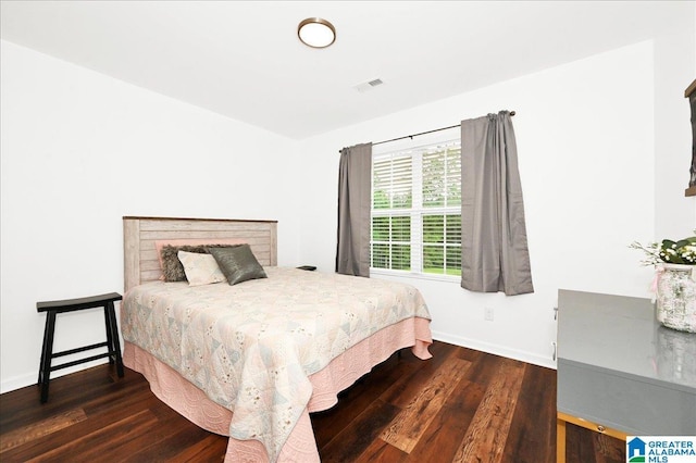 bedroom with visible vents, wood finished floors, and baseboards