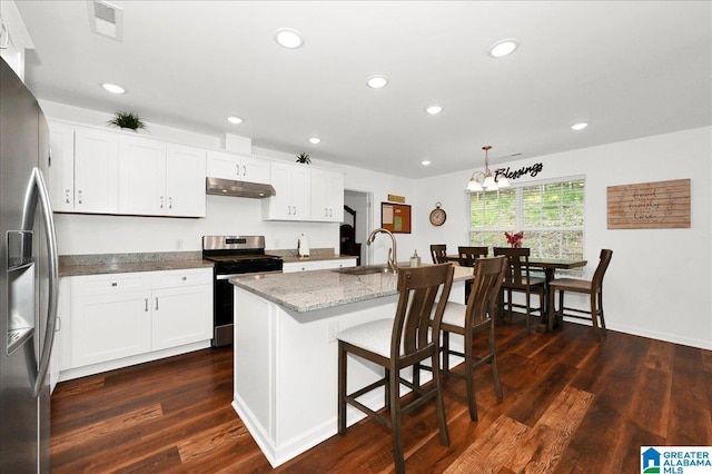 kitchen featuring a sink, dark wood-type flooring, light stone countertops, under cabinet range hood, and appliances with stainless steel finishes