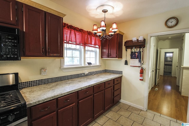 kitchen featuring dark brown cabinets, light tile patterned flooring, gas range, black microwave, and a chandelier