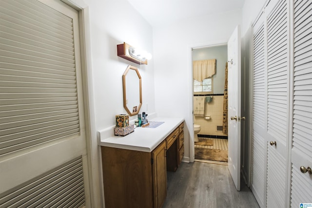 bathroom featuring a closet, toilet, wood finished floors, and vanity