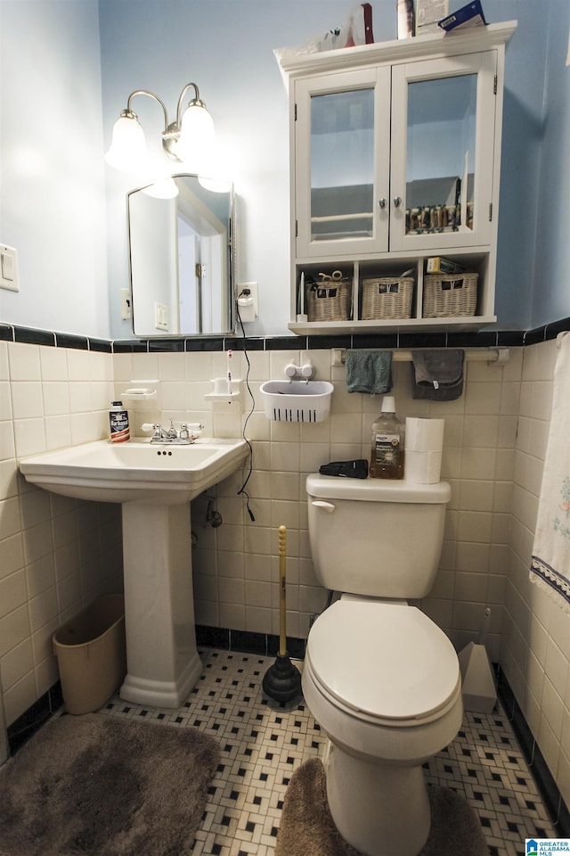 bathroom with wainscoting, tile patterned flooring, tile walls, and toilet