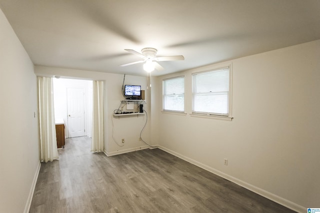 spare room with baseboards, ceiling fan, and wood finished floors