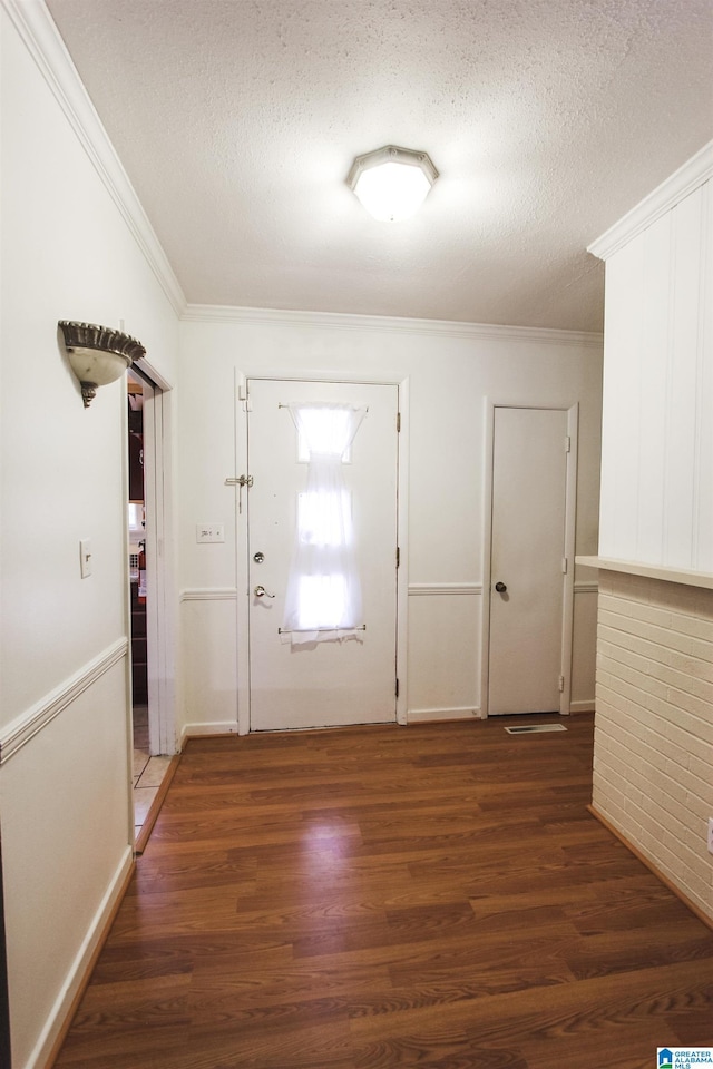 entrance foyer featuring ornamental molding, a textured ceiling, and wood finished floors