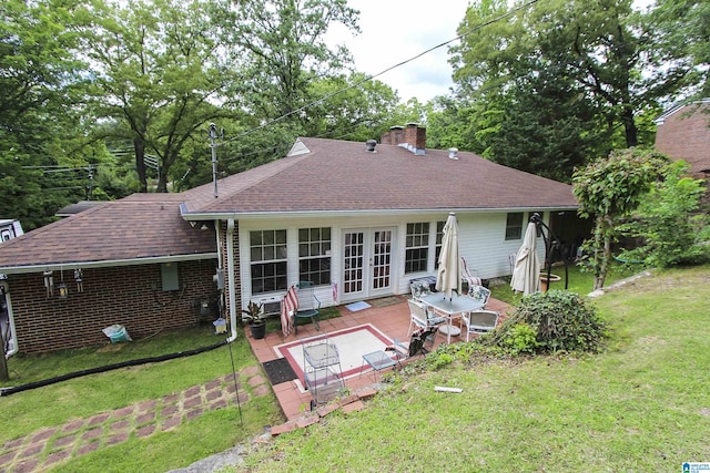back of property with a shingled roof, a yard, a chimney, and french doors