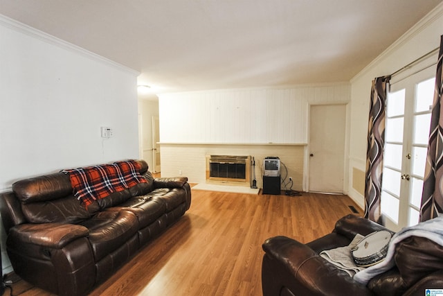 living room with light wood-type flooring, a glass covered fireplace, and crown molding