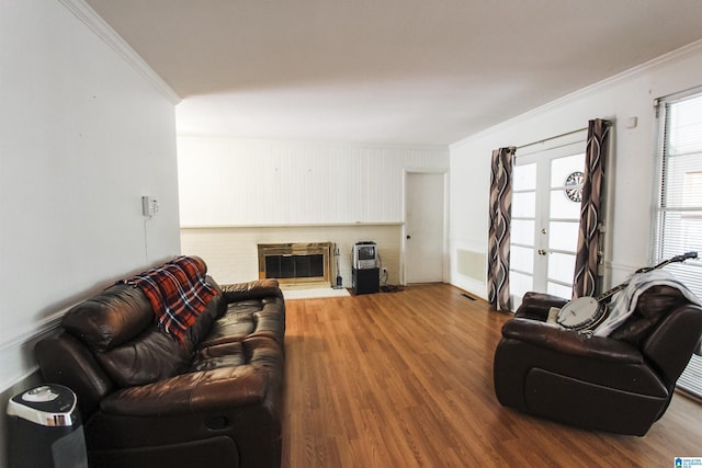 living area with a glass covered fireplace, crown molding, and wood finished floors