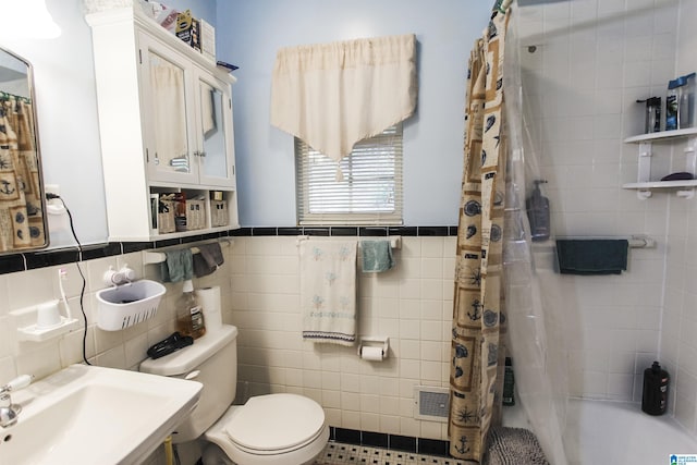 full bath with a sink, toilet, tile walls, a wainscoted wall, and curtained shower