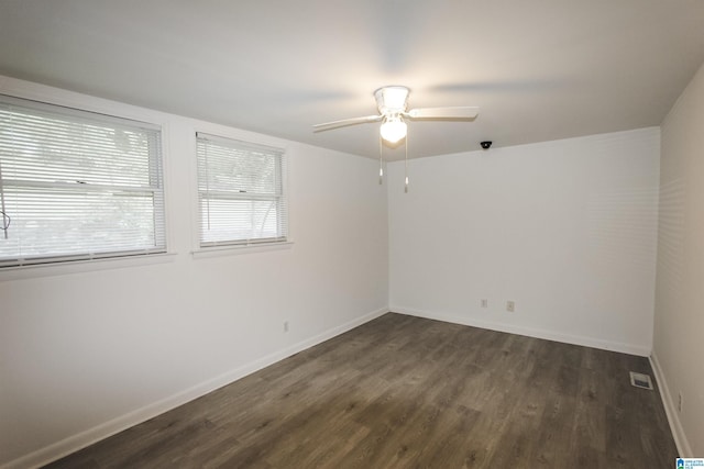 empty room with a ceiling fan, baseboards, visible vents, and dark wood-style floors
