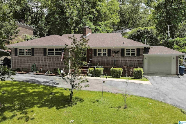 view of front of property with a front yard, brick siding, a chimney, and a garage