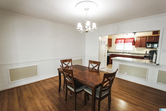 dining space with ornamental molding, a notable chandelier, and wood finished floors