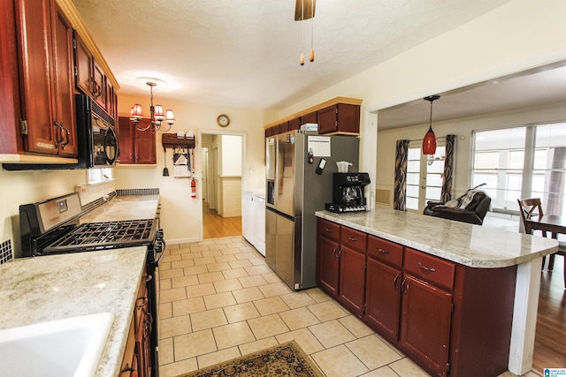 kitchen with a peninsula, reddish brown cabinets, stainless steel appliances, and a chandelier