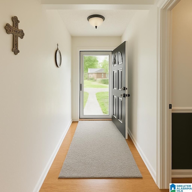 doorway featuring baseboards and light wood-style flooring