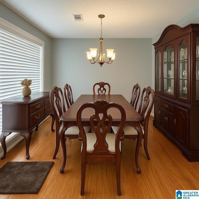 dining space with an inviting chandelier, light wood-style flooring, and visible vents