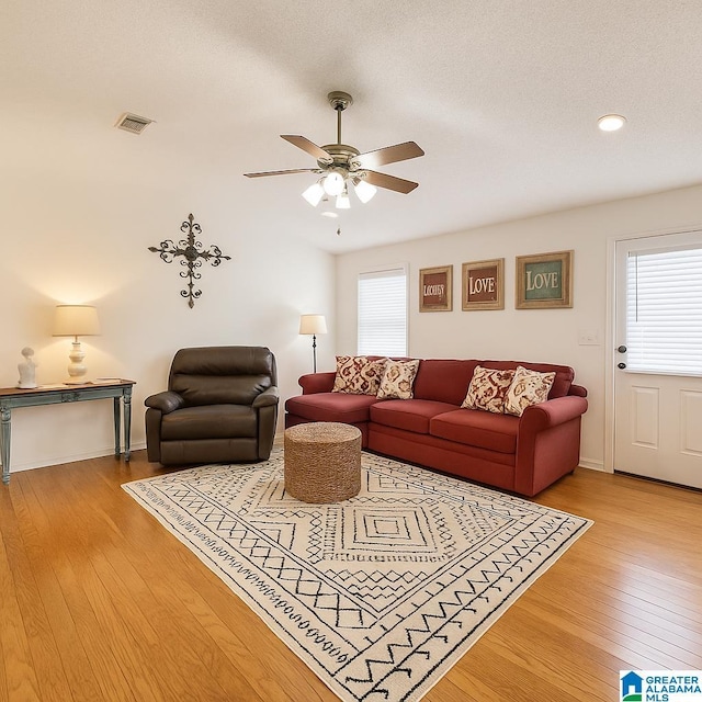 living room featuring a ceiling fan, baseboards, visible vents, and hardwood / wood-style flooring