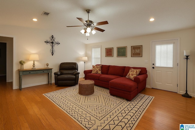 living room featuring baseboards, light wood-style floors, ceiling fan, and plenty of natural light