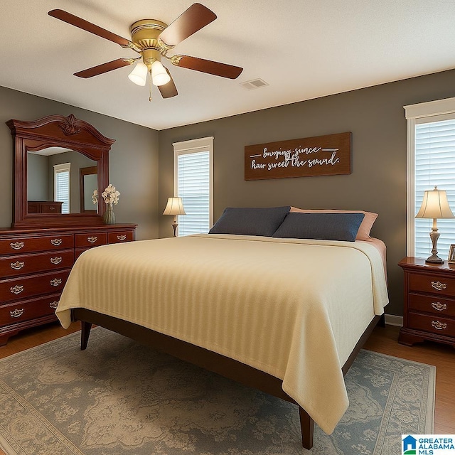 bedroom featuring a ceiling fan, visible vents, and dark wood-style floors