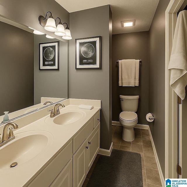 bathroom featuring a sink, double vanity, toilet, and tile patterned floors