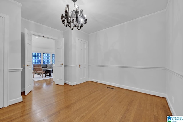 spare room with wood finished floors, a chandelier, and ornamental molding