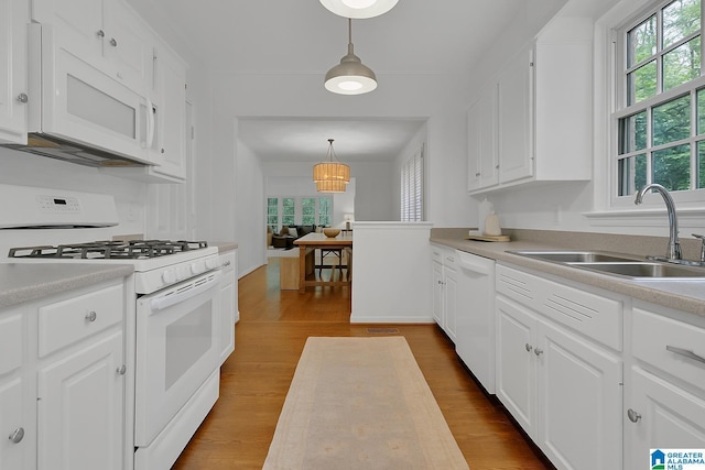 kitchen with white appliances, a sink, healthy amount of natural light, and light countertops