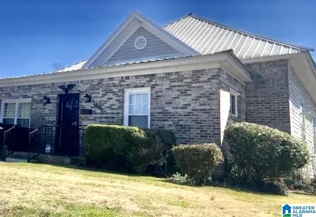 2121 47th Pl, Birmingham, AL 35208 - view of property exterior featuring brick siding, metal roof, and a lawn