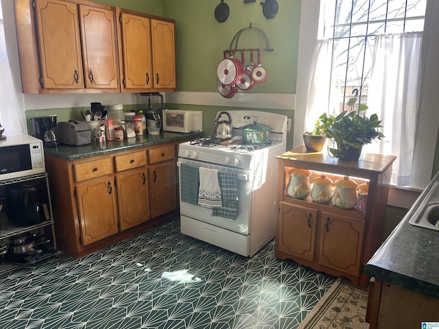 2121 47th Pl, Birmingham, AL 35208 - kitchen featuring brown cabinetry, white appliances, and dark countertops