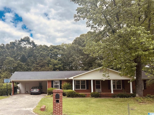 ranch-style home with covered porch, a carport, concrete driveway, a front lawn, and brick siding