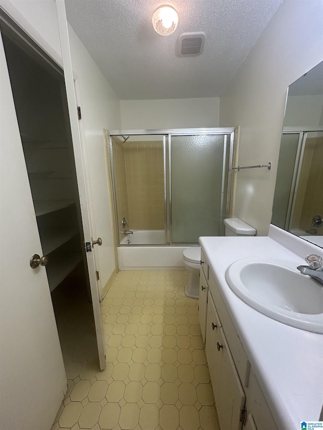 full bathroom featuring toilet, vanity, a textured ceiling, visible vents, and tile patterned floors