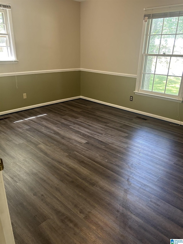 empty room with visible vents, baseboards, and dark wood-style floors